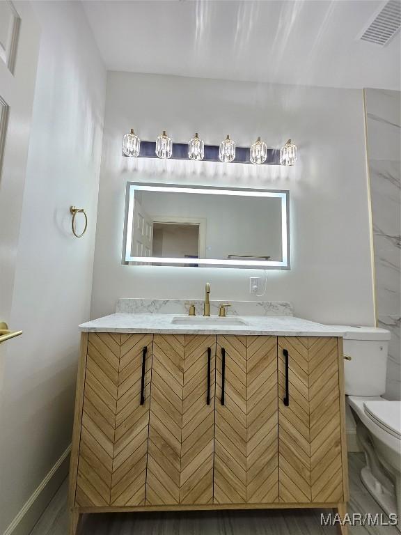 bathroom with vanity, toilet, and visible vents