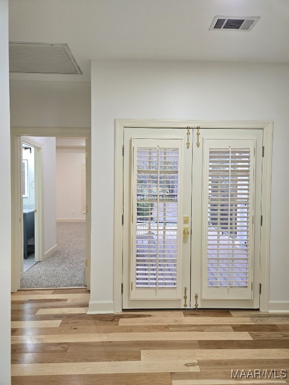 entryway with wood finished floors, visible vents, french doors, and baseboards