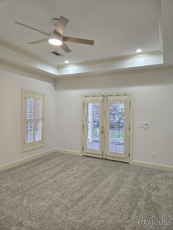 unfurnished room with visible vents, carpet floors, a tray ceiling, ceiling fan, and ornamental molding