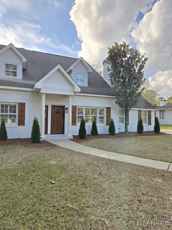 view of front of house featuring a front yard and a shingled roof