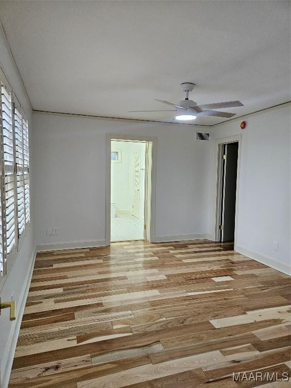 unfurnished room featuring visible vents, baseboards, ceiling fan, and wood finished floors