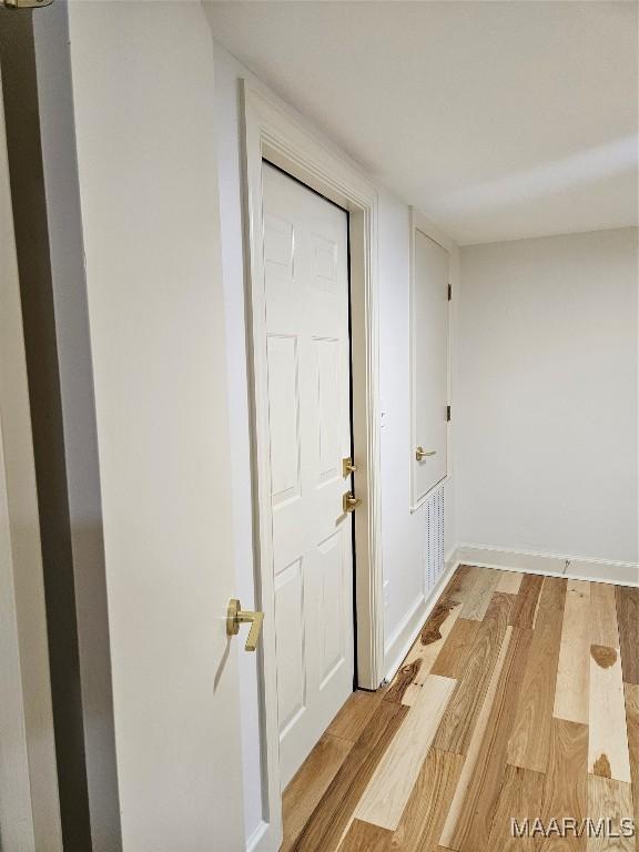 corridor with light wood finished floors and baseboards