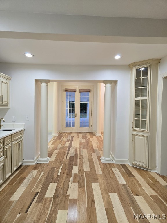 hall with french doors, baseboards, light wood finished floors, and a sink