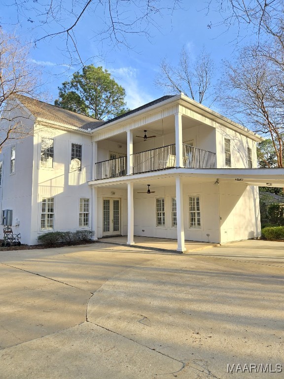 back of house with french doors, a balcony, a ceiling fan, and stucco siding