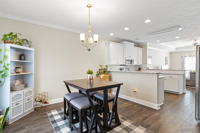 dining area with dark wood finished floors, ceiling fan with notable chandelier, and ornamental molding