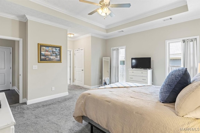 bedroom featuring visible vents, a tray ceiling, carpet flooring, crown molding, and baseboards