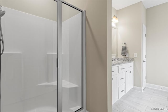 bathroom featuring vanity, a shower stall, and baseboards