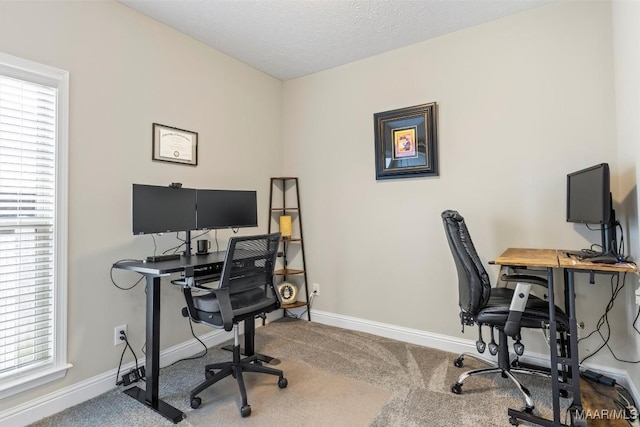 carpeted office space featuring baseboards and a textured ceiling