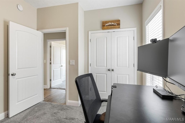 carpeted home office featuring baseboards