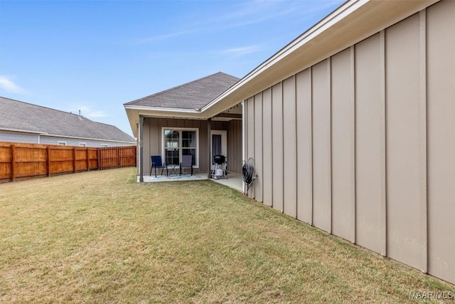 rear view of property featuring a yard, a patio, board and batten siding, and fence