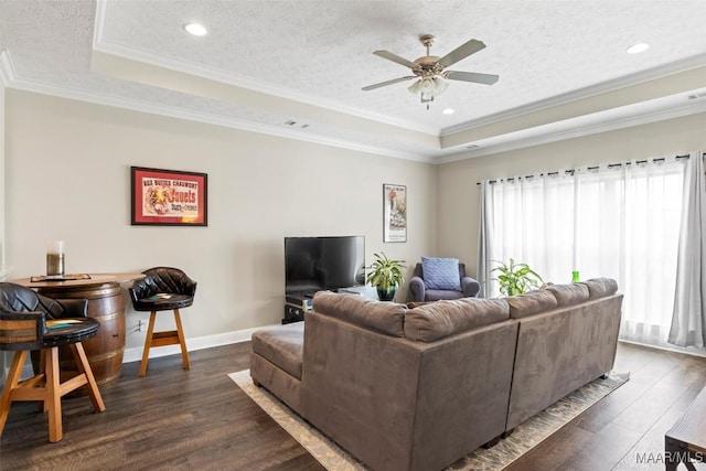 living room with a raised ceiling, a textured ceiling, dark wood finished floors, and a ceiling fan