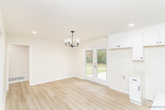 unfurnished dining area featuring a notable chandelier, baseboards, visible vents, and light wood finished floors