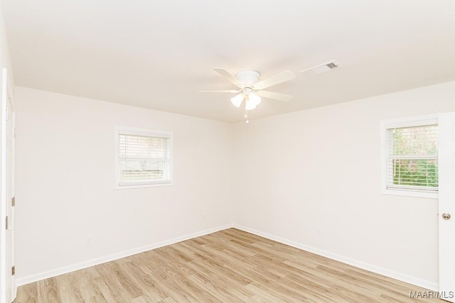 spare room featuring light wood finished floors, visible vents, baseboards, and ceiling fan