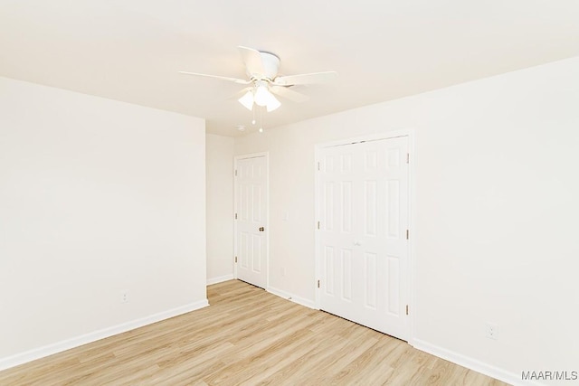 empty room with ceiling fan, light wood-type flooring, and baseboards