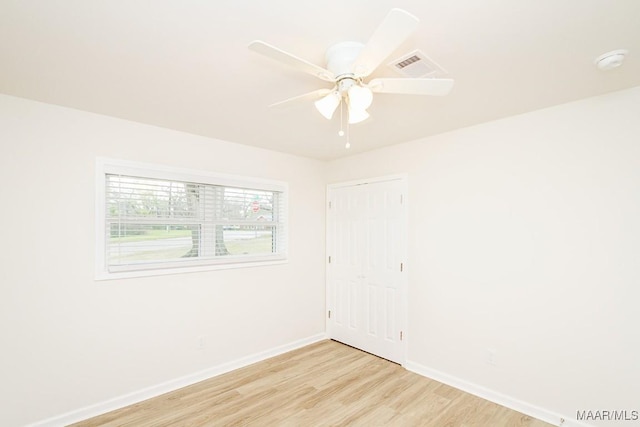unfurnished room featuring a ceiling fan, light wood-style flooring, baseboards, and visible vents