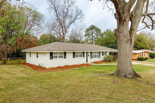 ranch-style house featuring roof with shingles, a front yard, and fence