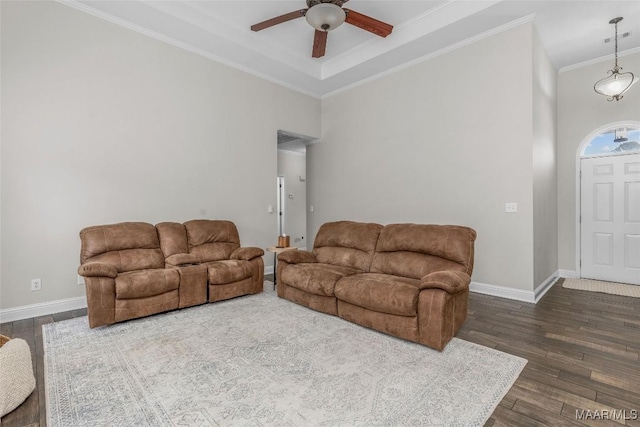 living area featuring baseboards, dark wood-style flooring, ornamental molding, and a ceiling fan