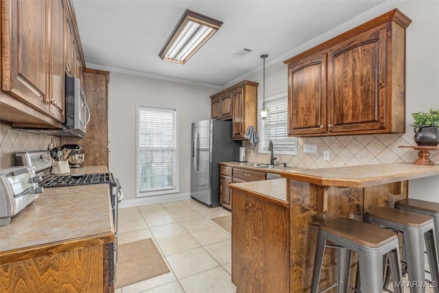 kitchen featuring ornamental molding, a kitchen breakfast bar, light tile patterned floors, and stainless steel appliances