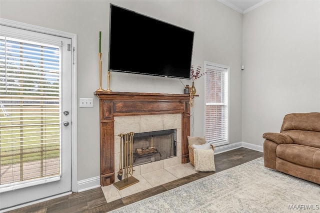 living room featuring a fireplace, wood finished floors, baseboards, and ornamental molding