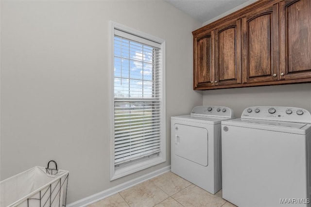 laundry area with baseboards, cabinet space, light tile patterned flooring, and washer and clothes dryer