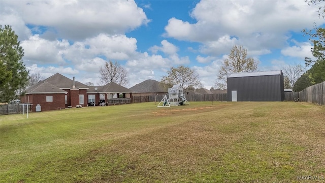 view of yard featuring an outdoor structure, a fenced backyard, and a playground