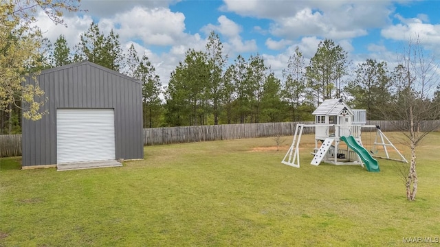 view of yard featuring a fenced backyard, a detached garage, a playground, and an outdoor structure