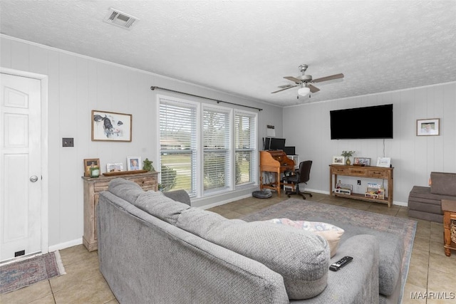 living room featuring light tile patterned floors, visible vents, a textured ceiling, and ceiling fan