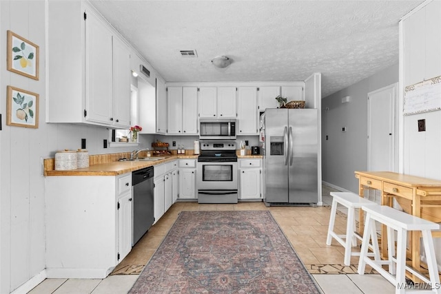 kitchen with visible vents, light countertops, appliances with stainless steel finishes, white cabinets, and a sink