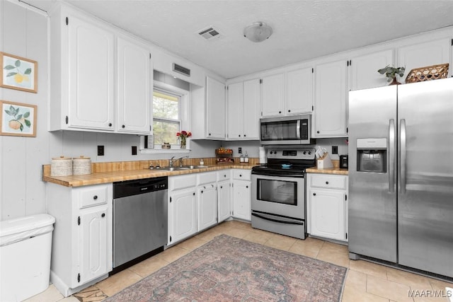 kitchen with a sink, visible vents, appliances with stainless steel finishes, and white cabinets