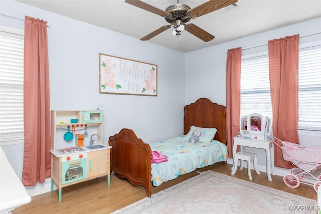 bedroom featuring visible vents, ceiling fan, a textured ceiling, and light wood-style floors