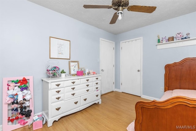 bedroom with baseboards, light wood-style flooring, a textured ceiling, and a ceiling fan