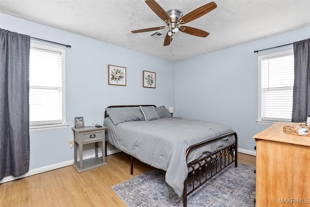 bedroom featuring multiple windows, wood finished floors, visible vents, and a textured ceiling