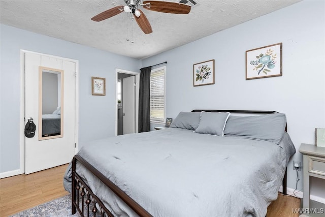 bedroom with baseboards, a textured ceiling, wood finished floors, and a ceiling fan