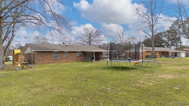 back of property featuring a playground, a trampoline, a lawn, and brick siding