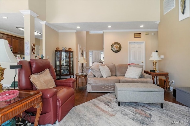 living area featuring visible vents, recessed lighting, dark wood-style flooring, a towering ceiling, and crown molding