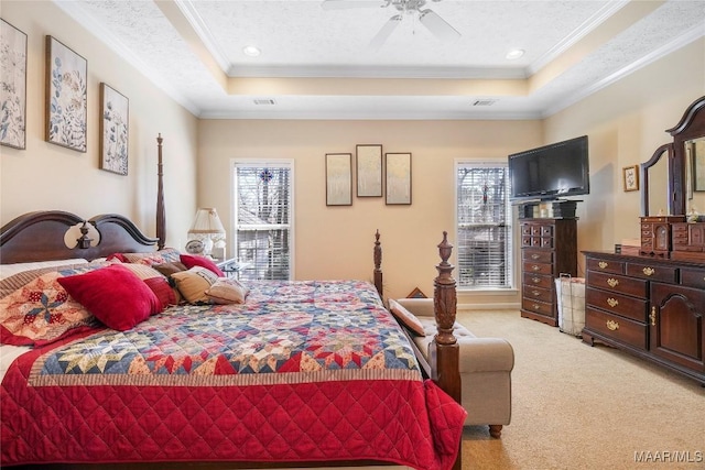 bedroom with a tray ceiling, multiple windows, and light colored carpet