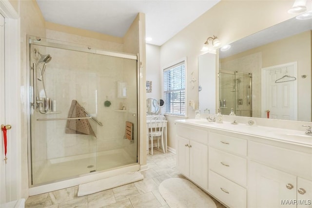 bathroom featuring a shower stall, double vanity, and a sink