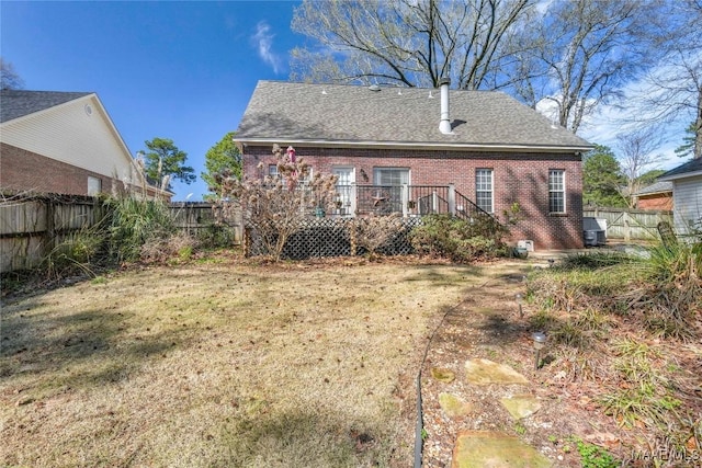 back of property featuring brick siding, a fenced backyard, a shingled roof, and a deck