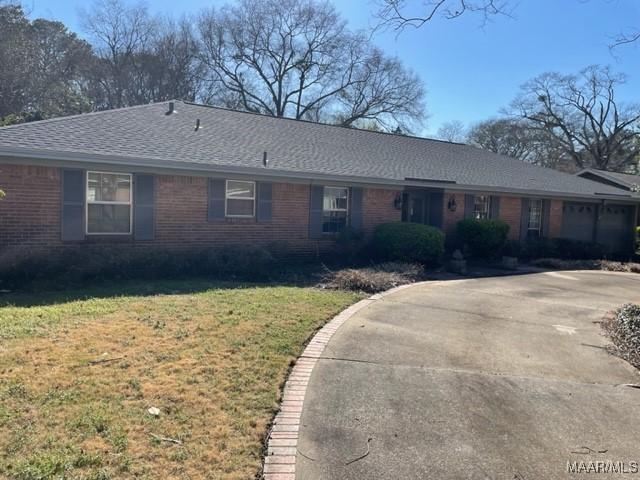 ranch-style home featuring a front lawn, brick siding, and roof with shingles