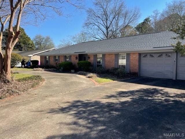 single story home featuring brick siding, an attached garage, and driveway
