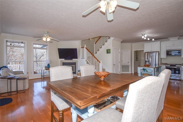 74 Lake Point Dr, Jacksons Gap, AL 36861 - dining room featuring light wood finished floors, a tiled fireplace, stairs, ornamental molding, and a ceiling fan