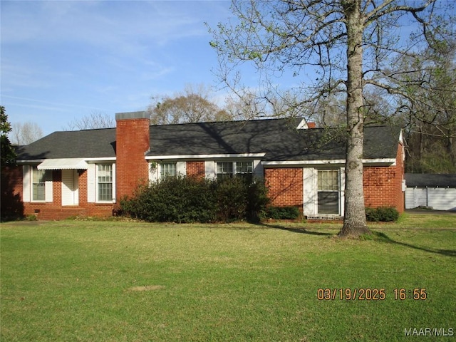 view of front of home featuring a front lawn, brick siding, and a chimney