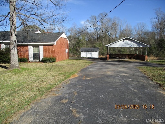 view of side of property with a detached carport, driveway, a yard, an outdoor structure, and a storage shed