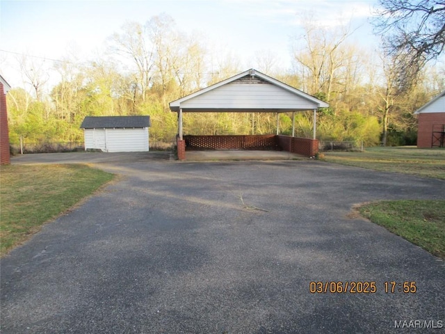 exterior space featuring aphalt driveway, a carport, and a shed