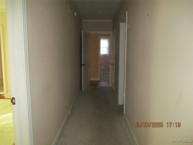 corridor with baseboards and crown molding