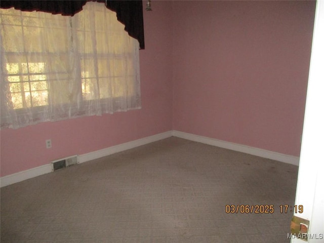 empty room featuring a healthy amount of sunlight, visible vents, and baseboards