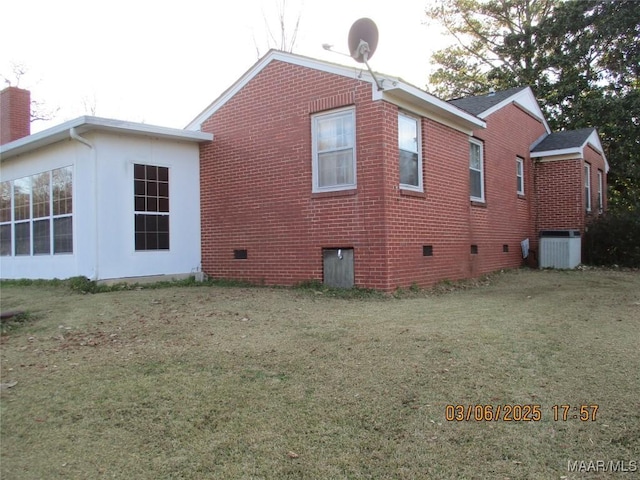 view of side of property featuring brick siding, central air condition unit, a lawn, and a chimney
