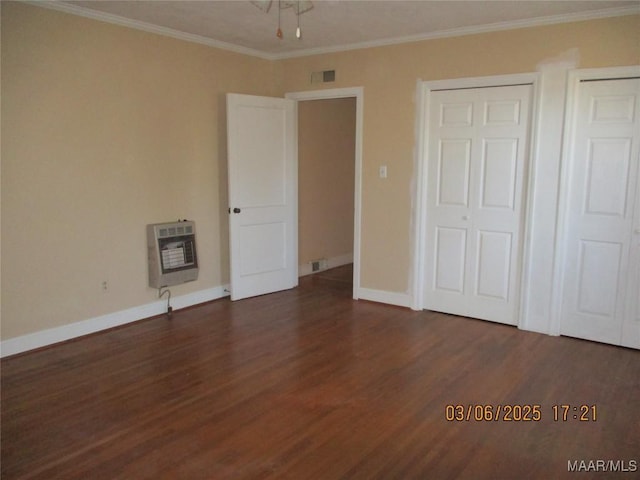 unfurnished bedroom featuring baseboards, heating unit, dark wood-style floors, and crown molding