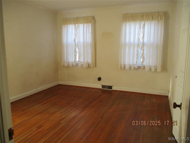 unfurnished room featuring dark wood finished floors, visible vents, baseboards, and ornamental molding