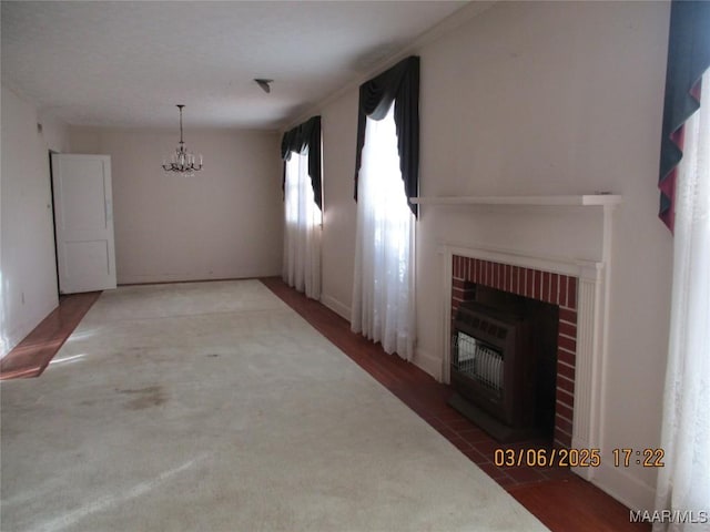 unfurnished living room featuring a chandelier, heating unit, and a brick fireplace